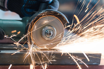 Cut metal with a Angular grinding machine. Sparks are flying. Construction tool grinder. A man is cutting metal. Wear gloves for safety.