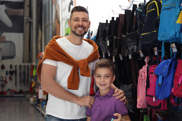 Fototapeta na wymiar Little school boy with father choosing backpack in supermarket