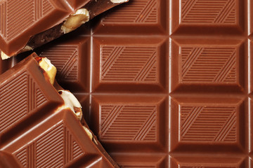 A bar and pieces of milk chocolate as a backdrop.