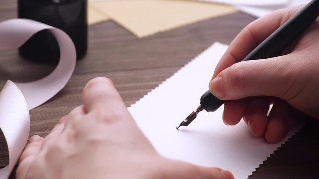 Close up view of hand writing with stylus and ink on the wedding invitation. Fine penmanship. Words wedding day. 4k.