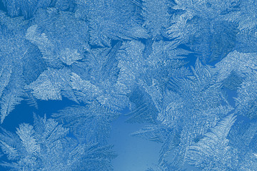 Close-up christmas or New year background in trendy color 2020 Classic Blue. Winter frosty pattern on window pane.