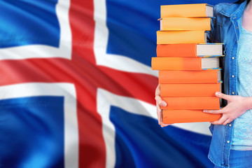 Iceland national education concept. Close up of female student holding colorful books with country flag background.