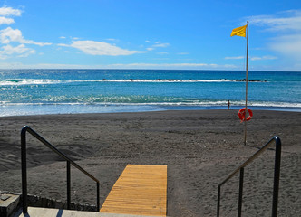 View of Playa del Duque beach with yellow flag on the south of Tenerife,Canary Islands,Spain.Travel or vacation concept.
