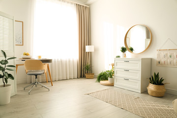 Stylish room interior with chest of drawers and round mirror