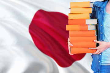 Japan national education concept. Close up of female student holding colorful books with country...