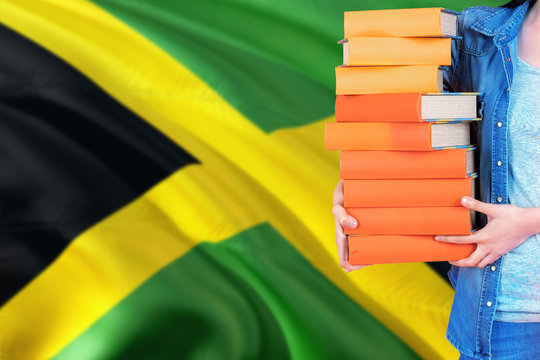 Jamaica national education concept. Close up of female student holding colorful books with country flag background.