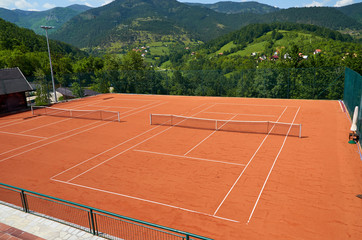 Fototapeta premium Empty outdoor tennis court in a picturesque landscape on a sunny day