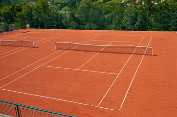 Empty outdoor tennis court in a lush surrounding on a sunny day