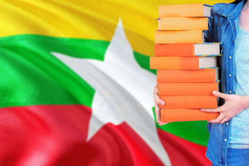 Myanmar national education concept. Close up of female student holding colorful books with country...