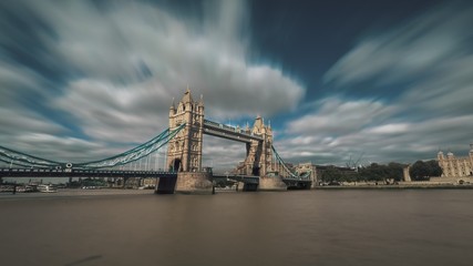Fototapeta na wymiar Bridge, Tower of London and The River Thames - iconic tourist attraction of England. Clouds flow in the sky, boats sailing. Travel recreation concept.
