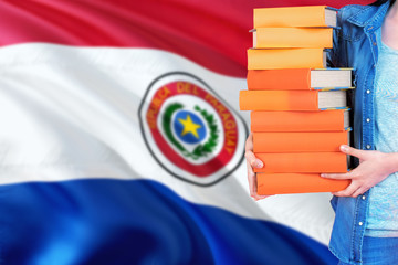 Paraguay national education concept. Close up of female student holding colorful books with country flag background.
