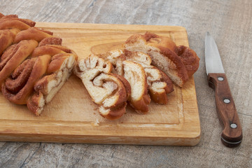 Twisted traditional Swedish cinnamon rolls at a café. The sweet buns are on a wooden chopping board.