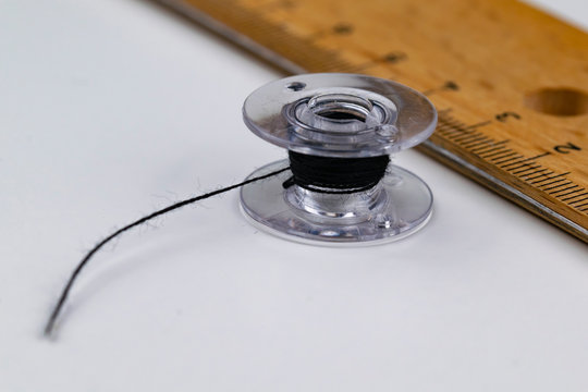 A bobbin and a ruler on a white table
