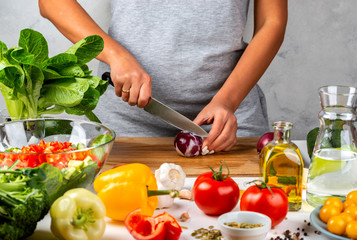 Woman cuts onions and makes salad in the kitchen. Healthy diet concept.