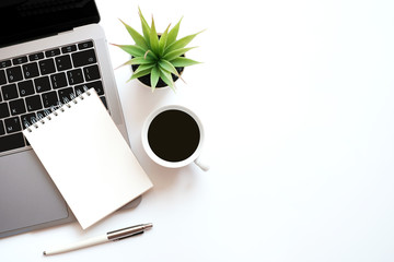 Work space office business and finance concept on modern table desk with blank notepad and laptop computer and coffee cup and green plant, Top view with copy space, flat lay