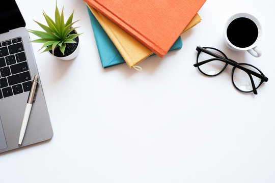 Flat lay business and education concept on modern table desk background with laptop computer and stack of book, glasses and coffee cup, top view and copy space