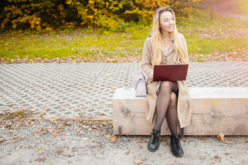 Young sensitive woman using laptop computer outdoor in the park. Freelance work concept. Learning...
