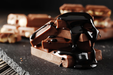 melted chocolate pouring into a piece of chocolate bars on a dark table. Top view. Place for text.