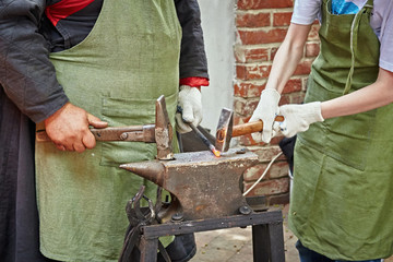 Two blacksmiths, an experienced one and his apprentice