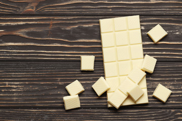 White chocolate slices and a bar on a brown table. Top view. Place for text.