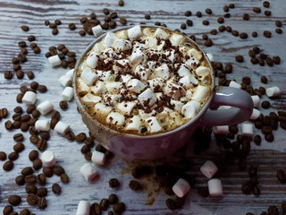  close-up of a hot drink, a cup of coffee / cocoa with marshmallows and chocolate chips on an abstract wooden surface background
