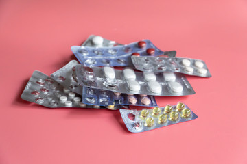 different blisters packages with tablets on pink background