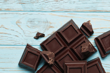 Black chocolate big pieces on a blue wooden background. Top view. Place for text.