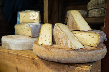 Cantal or saint nectaire french mature morbier cheese on the wooden shelf stored for sale or use organic food market