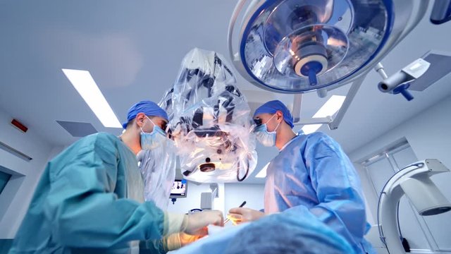 Surgeons during operation. Two professional doctors perform an operation together through the microscope. Modern equipment in the operating room.