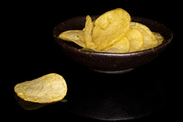 Lot of whole crisp potato chip in glazed bowl isolated on black glass