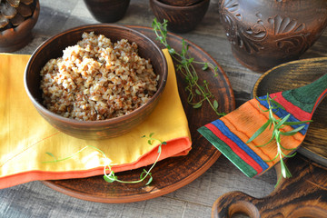Boiled organic buckwheat porridge in a ceramic bowl on rustic wooden table