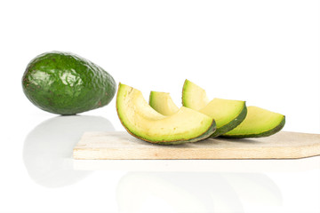 Group of one whole four slices of fresh green avocado on wooden cutting board isolated on white background