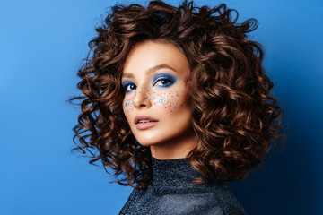 Portrait of Beautiful Woman with Sparkles on her Face. Fashion Model with Colorful Makeup