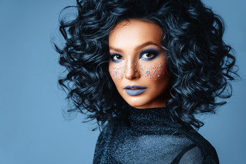 Portrait of Beautiful Woman with Sparkles on her Face. Fashion Model with Colorful Makeup