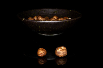 Lot of whole tasty brown hazelnut in glazed bowl isolated on black glass