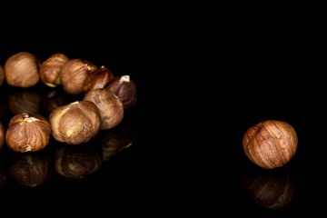 Lot of whole arranged tasty brown hazelnut isolated on black glass