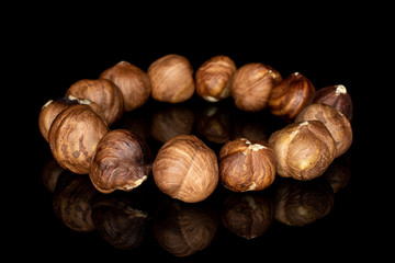 Lot of whole tasty brown hazelnut circle isolated on black glass