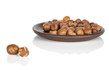 Lot of whole peeled tasty brown hazelnut with brown ceramic coaster isolated on white background