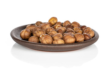 Lot of whole tasty brown hazelnut with brown ceramic coaster isolated on white background