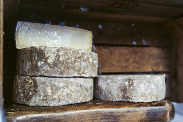 Cantal or saint nectaire french mature cheese on the wooden shelf stored for sale or use organic food