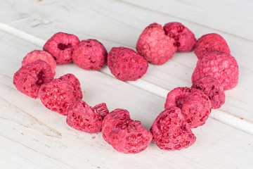 Lot of whole dried raspberry heart on white wood
