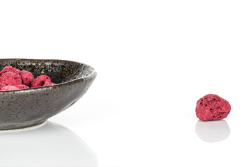 Lot of whole dried raspberry in glazed bowl isolated on white background
