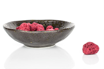Lot of whole dried raspberry in glazed bowl isolated on white background