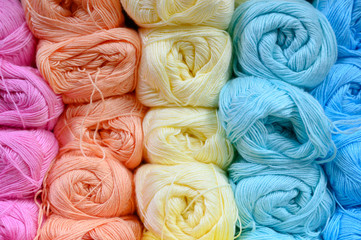 background of rows skeins of thin fluffy wool yarn for knitting different pastel colors. soft light color of pink, orange, yellow, mint and blue