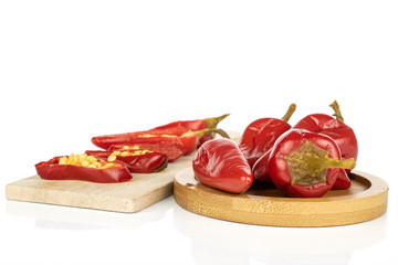 Group of four whole two halves two slices of pickled red pepper on wooden cutting board on round bamboo coaster isolated on white background