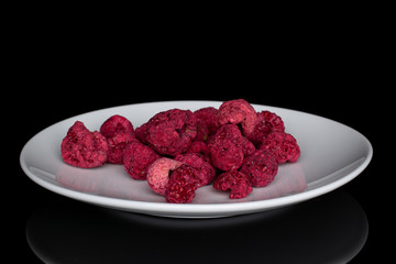 Lot of whole dried raspberry on white ceramic plate isolated on black glass