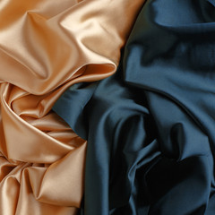 Wavy gold and blue silk, atlas or veil fabric, crumpled with creases, bended in spiral wrinkle