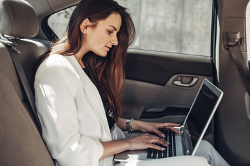 Fashion Stylish Girl in White Suit Works at Laptop in Car