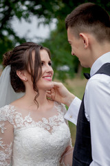 Beautiful newlyweds couple walking in the woods. Honeymooners. Bride and groom holding hand in pine forest.