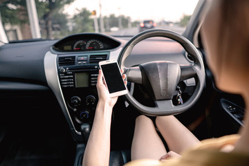 Young woman in car checking her smartphone while driving
